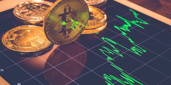 Moneta z symbolem Bitcoina i wykres symbolizujące mity o kryptowalutach